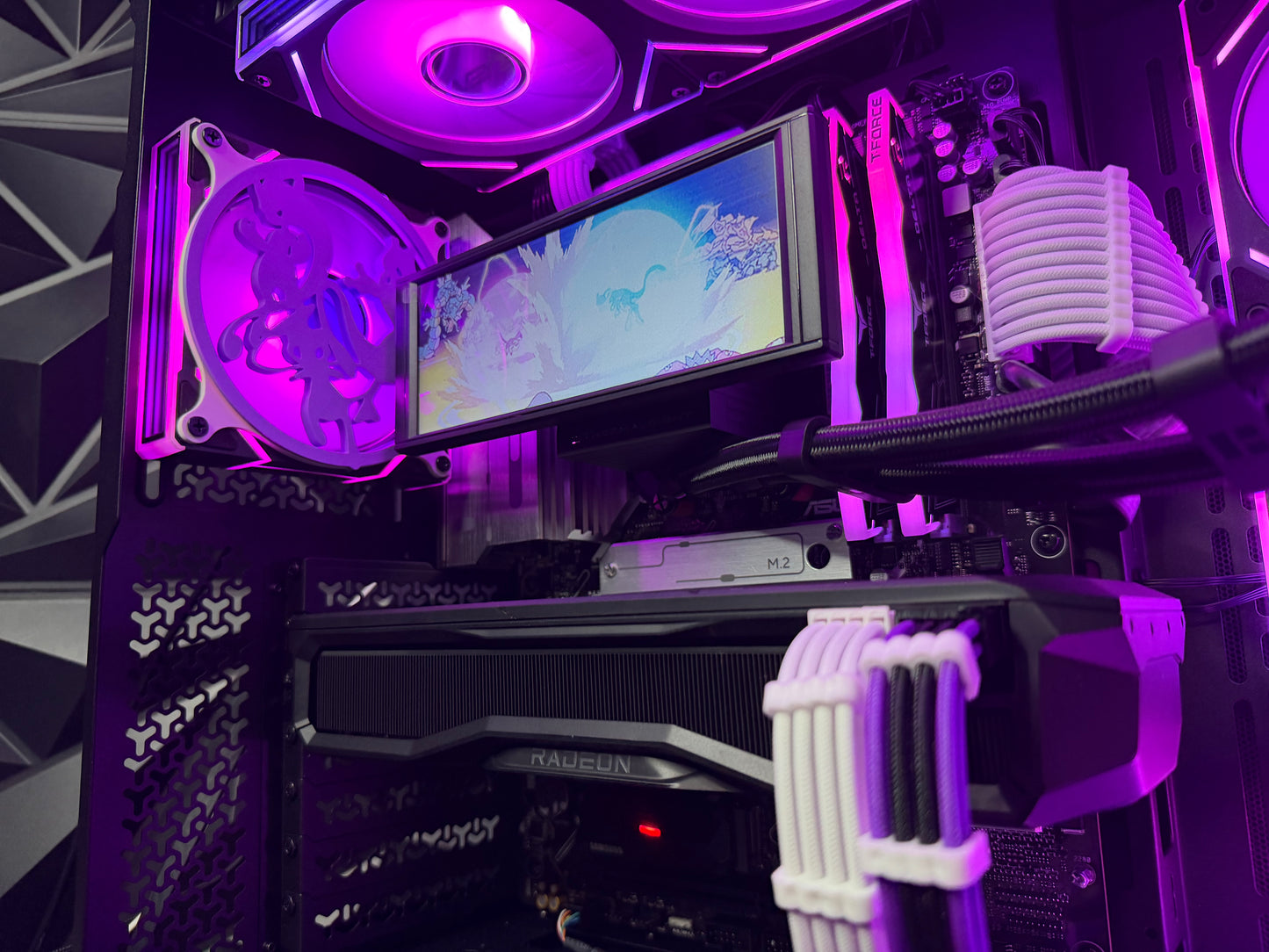 Close-up of a computer setup with a monitor, graphics card, and cooling components under purple lighting.